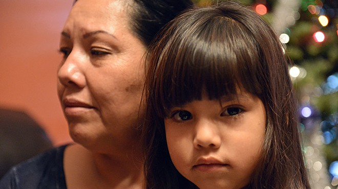 Erica Alvarado's daughter looks on while in the arms of her grandmother.