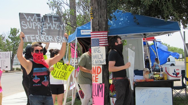 Protestors at San Antonio's small Occupy ICE encampment show off their signs.