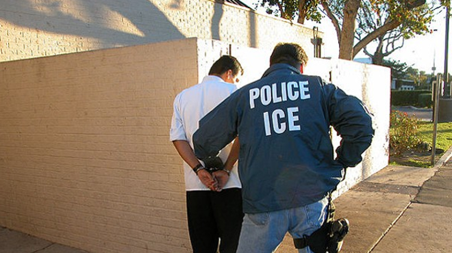 An ICE agent detains a suspect.