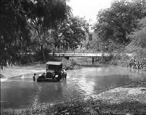 Automobile in San Antonio River in Roosevelt Park, circa 1927
In a time before cell phones, imagine coming home soaking wet to your spouse and having to explain that you drove the car into the river – but that’s not what happened at all. He’s actually washing it.
Photo via General Photograph Collection