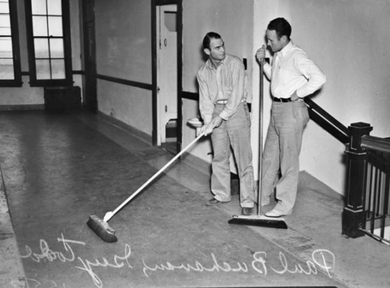 This 1937 photograph shows Guy Todd (left) and Clayton Holcomb, members of the St. Mary's football team, working as janitors for their part-time jobs.