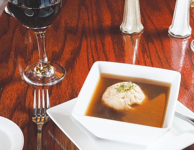 A single dumpling floats atop an honest bouillon soup. - WWW.PAYTONPHOTOGRAPHY.COM
