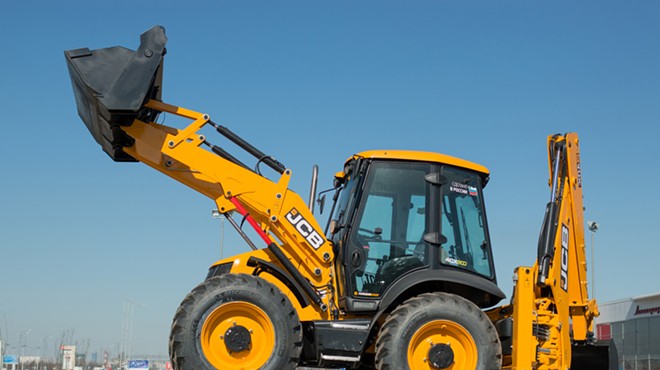 A JCB all-wheel drive backhoe loader stands on an advertisement stand.