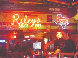 Chris Meekes tends bar under the neon lights at Riley’s Tavern.