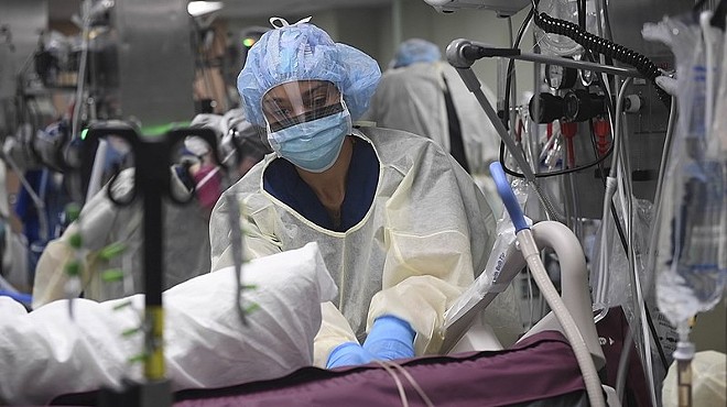A surgical nurse prepares a COVID-19 patient for a procedure in an intensive care unit.