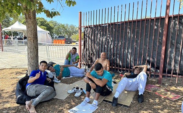 A group of Venezuelan migrants take refuge from the Texas sun under a tree outside San Antonio's Migrant Resource Center.