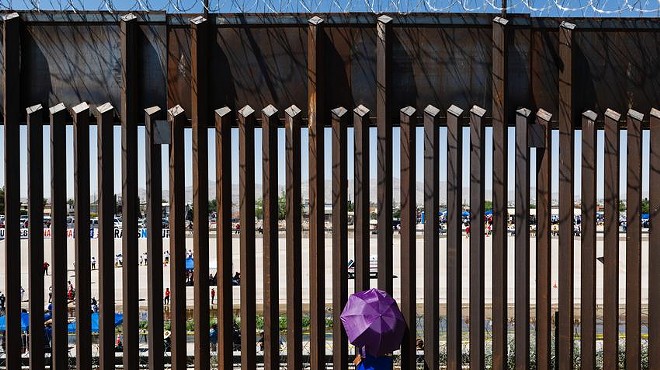 A woman looks through the border wall towards her family in Ciudad Juarez, Mexico from El Paso, Texas on June 19, 2021.