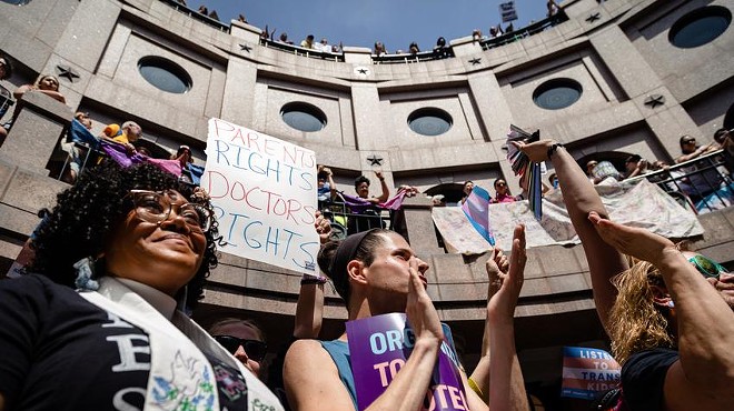 People line the railing on all three levels of the outdoor rotunda of the state Capitol in Austin, and wave signs during a "Fight for Our Lives" rally in opposition of anti-LGBTQ bills on March 27.