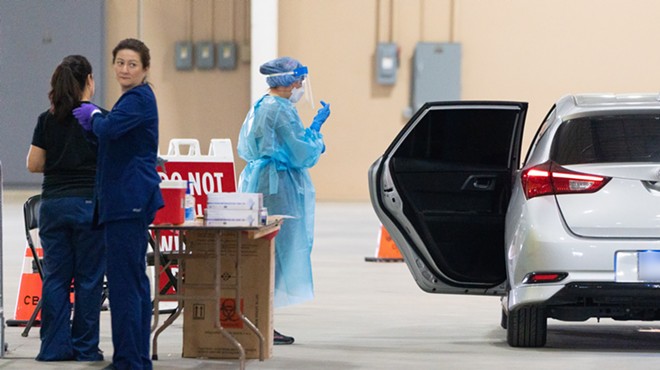 Healthcare workers assist with a drive-through coronavirus test at San Antonio's Freeman Coliseum site.