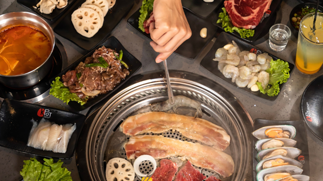 Restaurant customers cook meat and vegetables at a KPot Korean BBQ & Hot Pot.