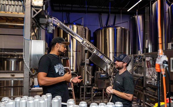 Marcus Baskerville, one of the founders of Weathered Souls Brewing Co., speaks to an employee on its production line in this 2021 photo.