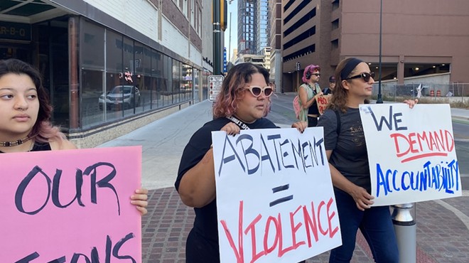 Protesters hold up signs in front of San Antonio city offices demanding accountability for the treatment of the community's unhoused population.