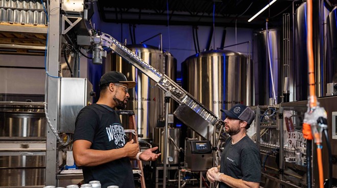 Marcus Baskerville, one of the founders of Weathered Souls Brewing Co., speaks to an employee on its production line in this 2021 photo.