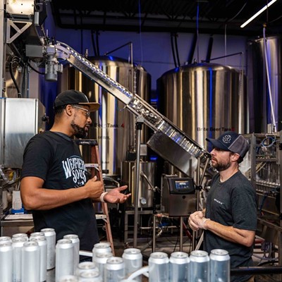 Marcus Baskerville, one of the founders of Weathered Souls Brewing Co., speaks to an employee on its production line in this 2021 photo.