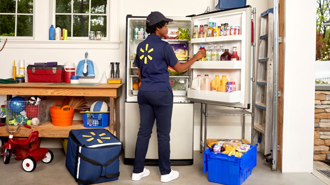 A Walmart+InHome delivery associate stocks a fridge.