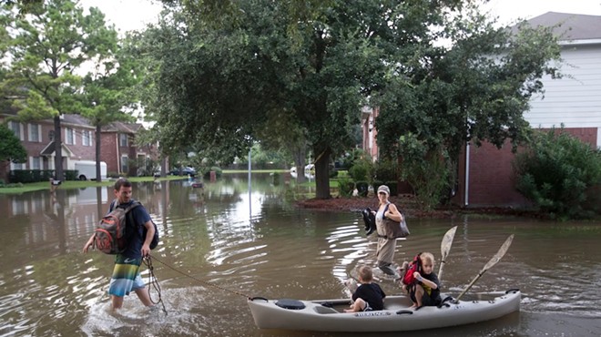 A family returns to their Houston home in a kayak on Aug 30, 2017 after their neighborhood was flooded by Tropical Storm Harvey. The widespread flooding from Harvey sparked the first statewide flood prevention plan, which is under development.