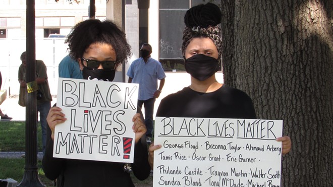 Two protesters hold up signs at a San Antonio march against police brutality.