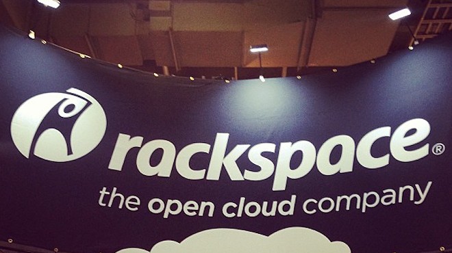 A banner hangs above a Rackspace display at a trade show.