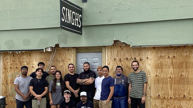 Employees of Singh's Vietnamese pose in front of the restaurant's now boarded-up storefront.