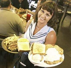 Stock Yards Cafe waitress Lillie Aldrich lifts orders of chicken fried steak with mashed potatoes and green beans and a bacon-cheese-chopped steak with fries and mac and cheese.
