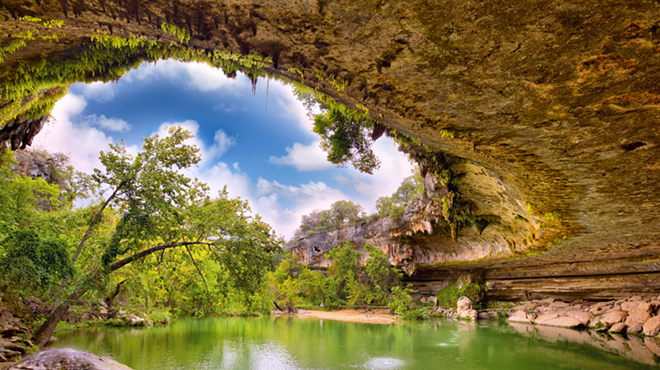 Water falls off the top section of rock into Hamilton Pool on a sunny day.