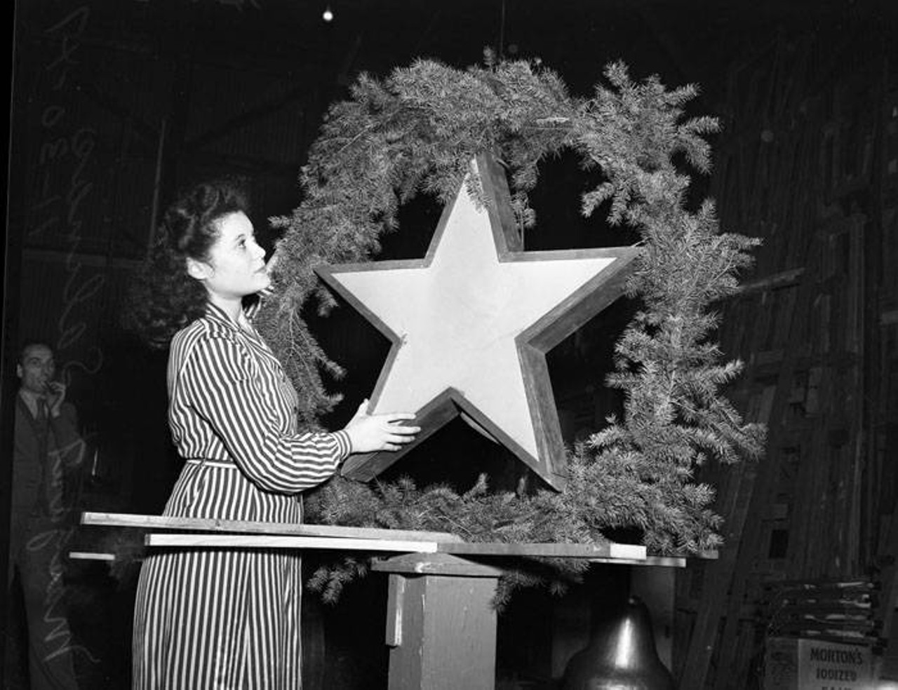 Sometimes you don't realize just how big Christmas decorations can be! Here, Margarett Salinas poses with one of the decorations destined to be hung downtown for the 1947 holiday season.