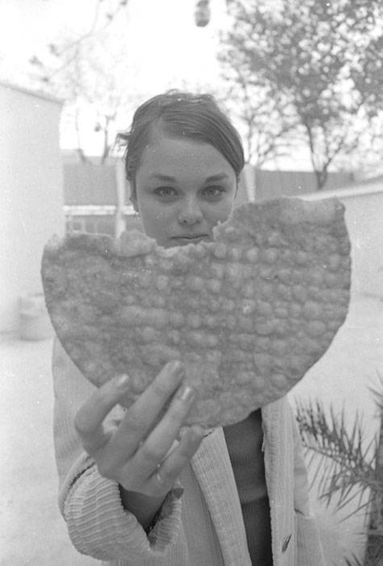 Young woman eating a bunuelo from Goliad Food Plaza (the food cluster)