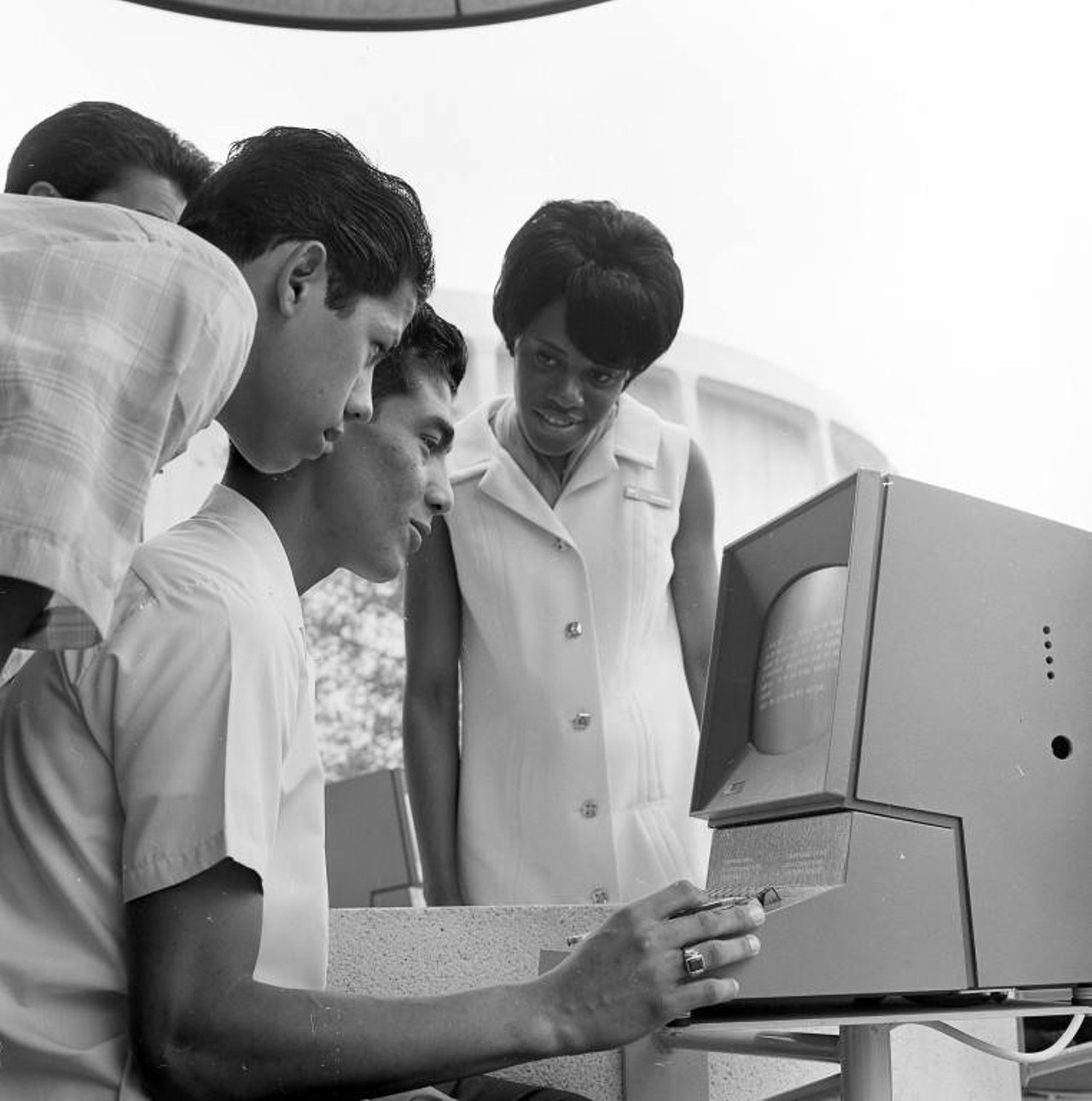 A pavilion guide assists a visitor who is using an IBM 2260 video display terminal to play a question-and-answer game in the IBM Durango Pavilion