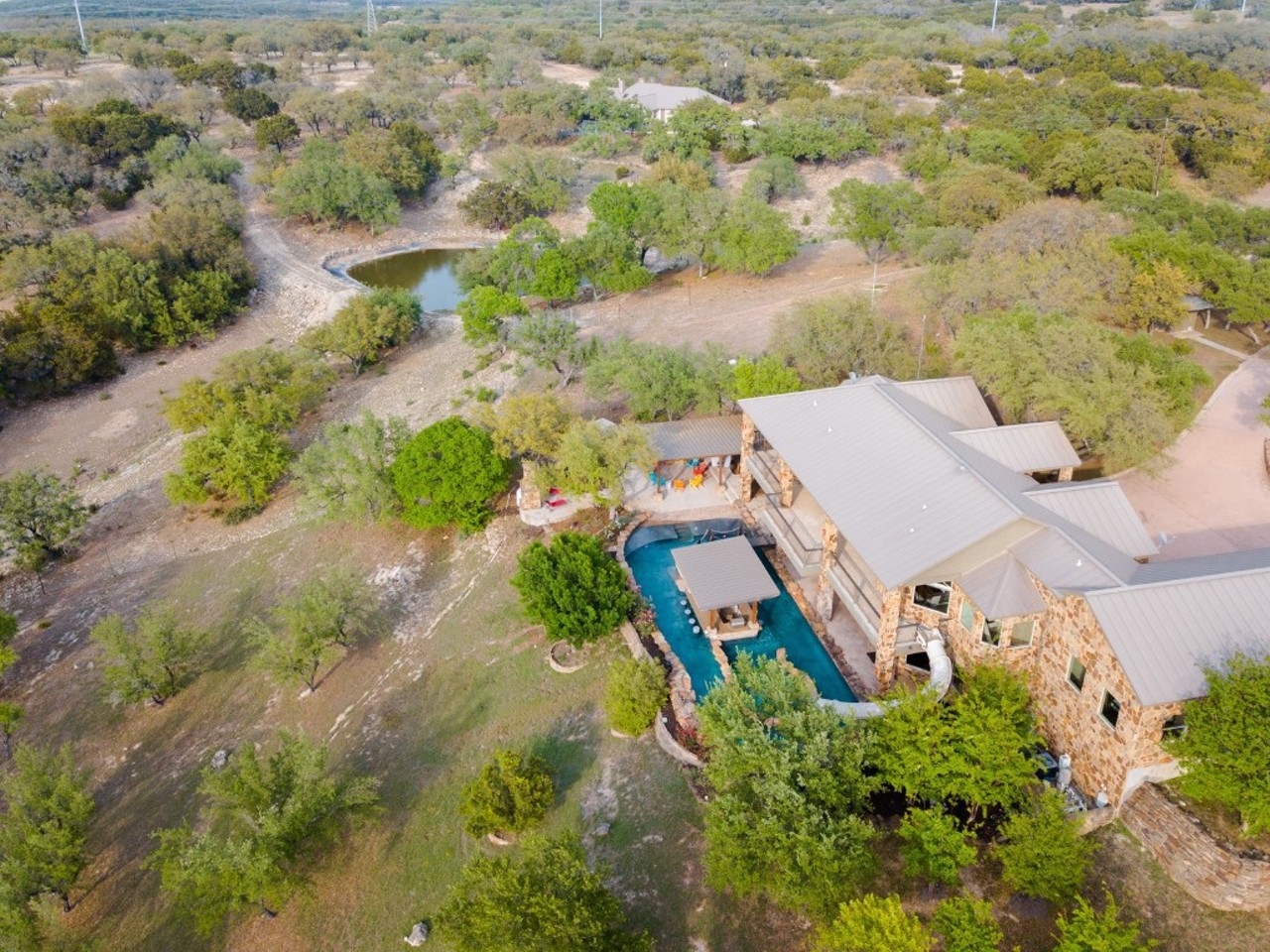 This Texas Hill Country mansion comes with a backyard lazy river and pool slide on its upper balcony