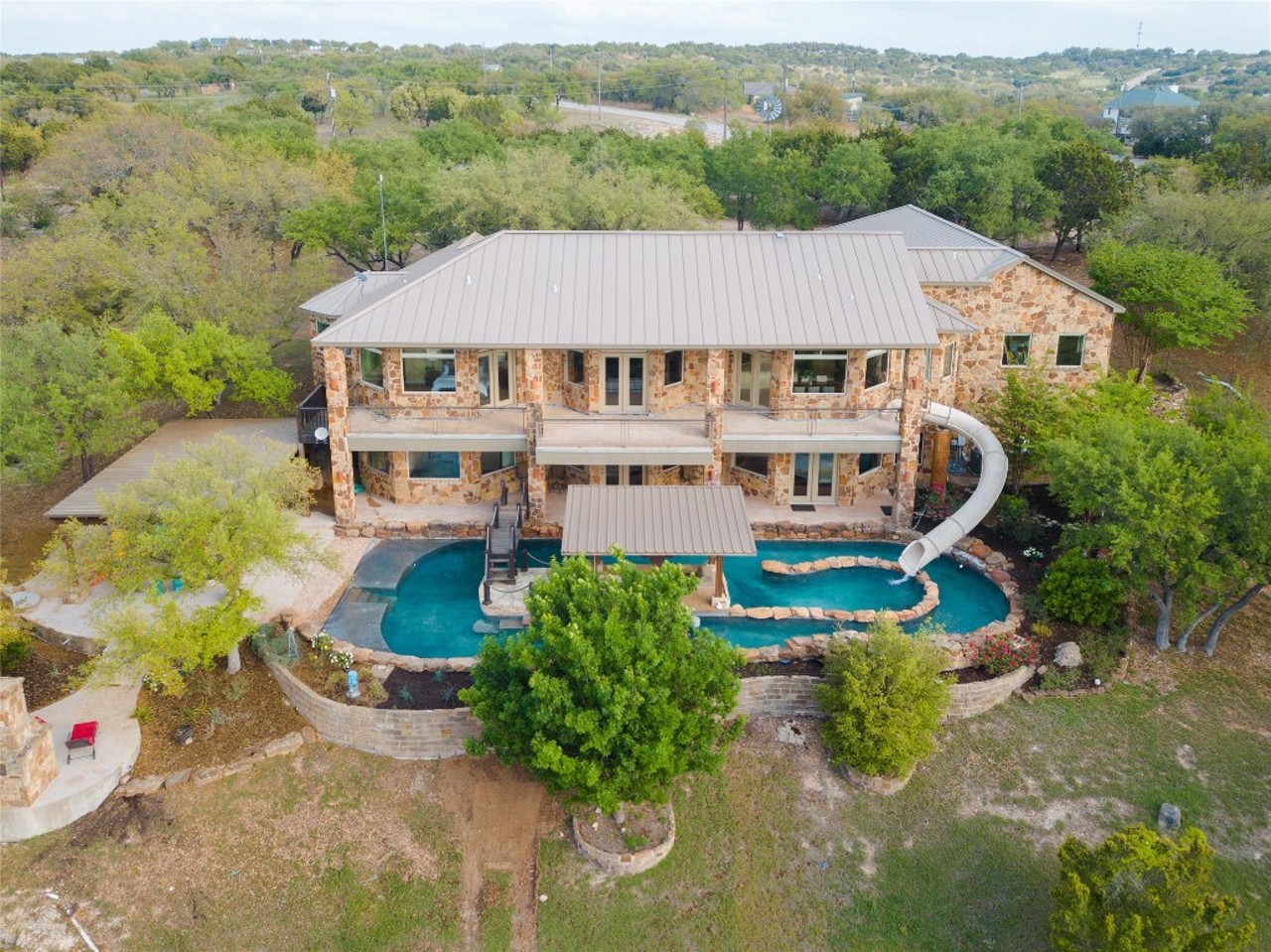 This Texas Hill Country mansion comes with a backyard lazy river and pool slide on its upper balcony