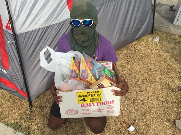 Occupy ICE San Antonio spokesman “Kazi” shows off a box of food and activity books the group gives out to people entering San Antonio’s ICE detention facility. - Sanford Nowlin