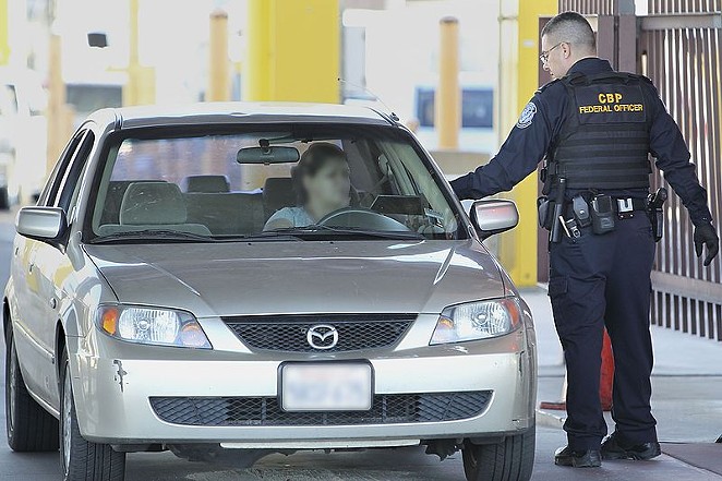 A border patrol officer checks a car crossing into the United States. - U.S. CUSTOMS AND BORDER PROTECTION