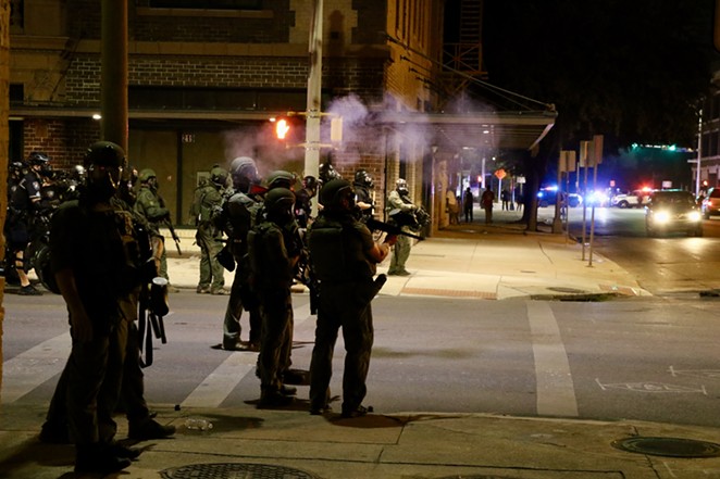 San Antonio police patrol downtown after using tear gas to clear demonstrators. - JAMES DOBBINS