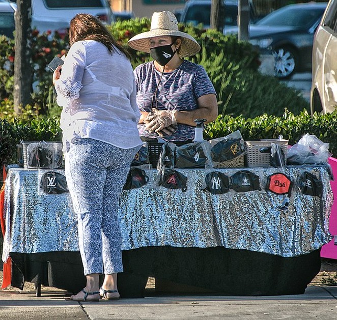 A woman shops for face masks with a sidewalk vendor. - WIKIMEDIA COMMONS / RUSS ALLISON LOAR