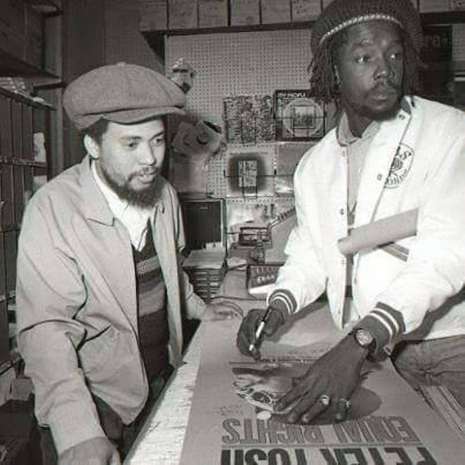 Peter Tosh (right) signing a poster for a fan. - Facebook