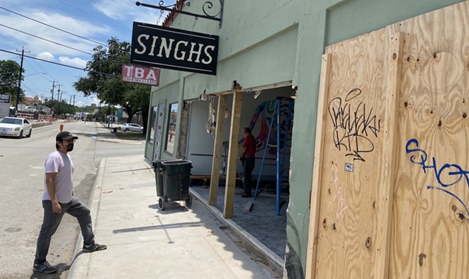 Eric Treviño, a partner in Singhs, watches a work crew clear debris out from the restaurant after it was struck by a car last weekend. - SANFORD NOWLIN