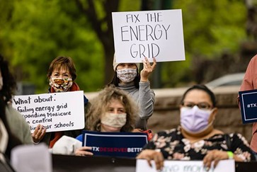 Activists held signs advocating for improvements to Texas’ energy grid at a progressive rally in April at the south gate of the state Capitol. - TEXAS TRIBUNE / JORDAN VONDERHAAR