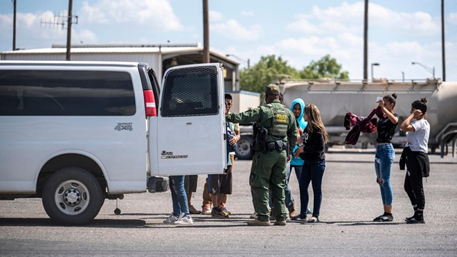 People who were apprehended by state troopers after crossing the border are brought to the International Bridge in Eagle Pass on May 28 to be handed over to Border Patrol custody. - Texas Tribune / Sergio Flores