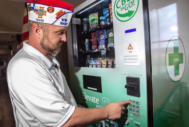 Dave Walden, wearing a Veterans of Foreign Wars cap, demonstrates how the CBD vending machine works by purchasing a product in Leander on Nov. 1. Credit: Azul Sordo/The Texas Tribune - Texas Tribune / Azul Sordo