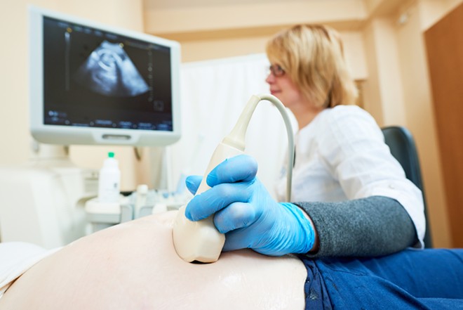 A physician conducts ultrasound on a pregnant patient. - Shutterstock.com