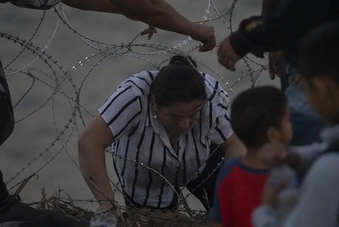 People pull concertina wire back so a Colombian woman can get though. - Texas Tribune / Verónica G. Cárdenas