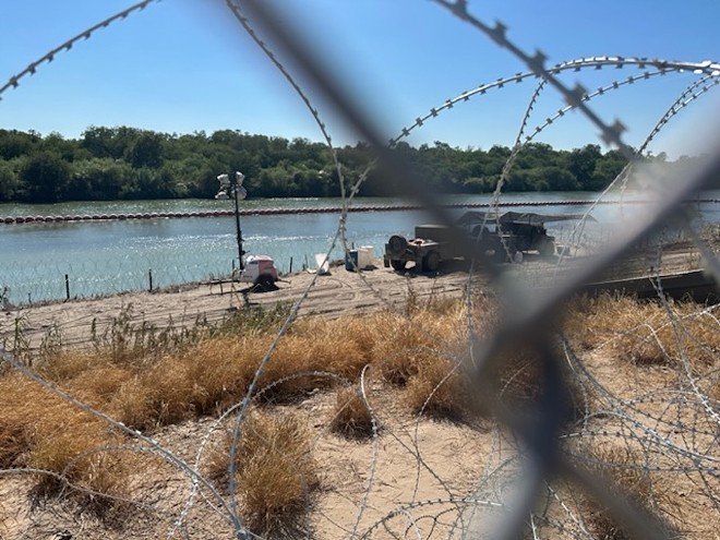 Texas Guard personnel involved in Operation Lone Star monitor the Rio Grande from behind a barrier of razor wire installed by the state. - Michael Karlis