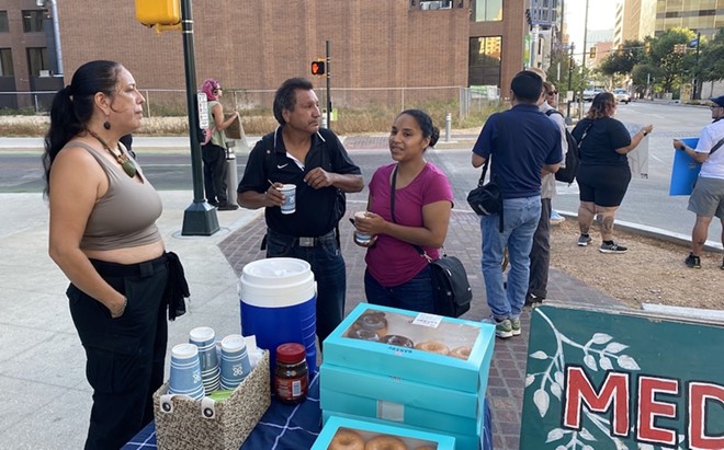 Maria Turvin (left) speaks to Alvino Acuna (center) and Roxanne Ybarra (right), who stopped for water. Ybarra, who's experienced homelessness, said she now works 80 hours a week to afford to live in a downtown hotel. - Sanford Nowlin