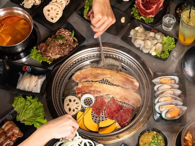 Restaurant customers cook meat and vegetables at a KPot Korean BBQ & Hot Pot. - Facebook / KPot Korean BBQ & Hot Pot