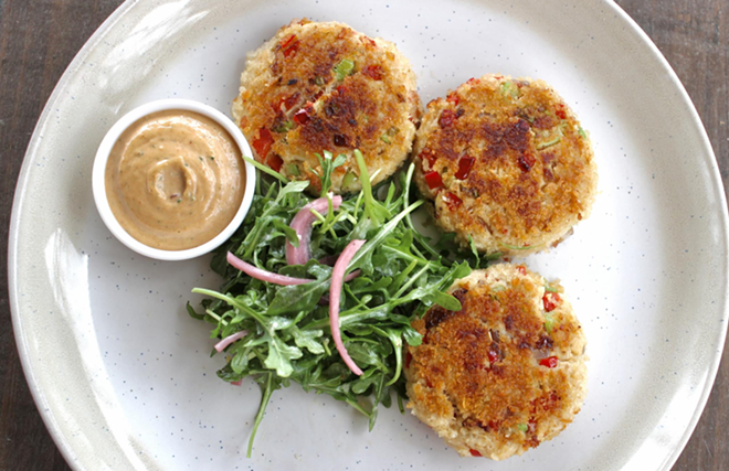 Rivulet's crab cakes are served with arugula salad, a side and remoulade. - Facebook / Rivulet Kitchen & Bar