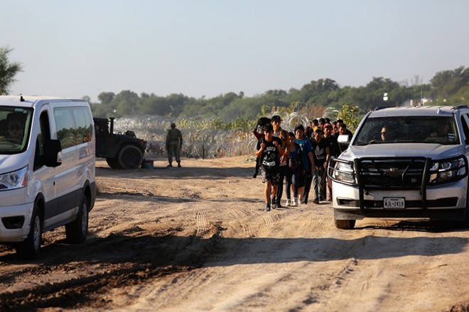 A group of migrants seeking U.S. asylum walk down a road beside the Rio Grande River to turn themselves in to the Border Patrol. - Shutterstock / Vic Hinterlang