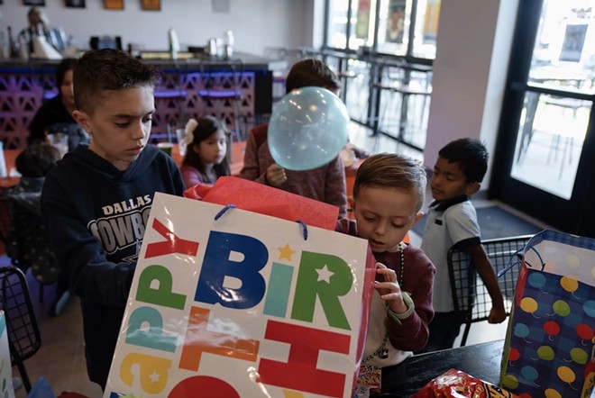 August opens his birthday presents while surrounded by friends, a few with similar diagnoses, on Dec. 9, 2023. It was his first birthday party — August spent three of his five birthdays in the hospital. - Texas Tribune / Azul Sordo