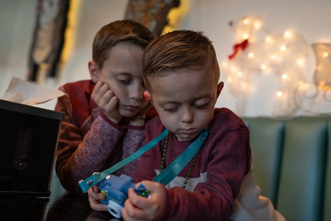 From right: August and his older brother Bryant play a game on his toy camera. - Texas Tribune / Azul Sordo