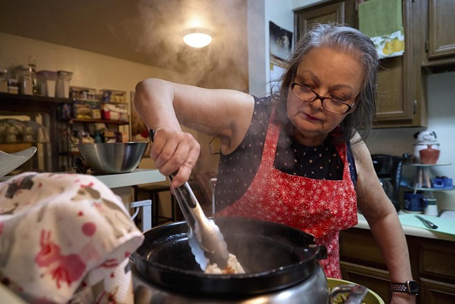 Mary Ann Estrella stirs a pot of homemade dog food inside her kitchen. Estrella makes her own dog food to save money as living costs increase. - Texas Tribune / Reilly Strand