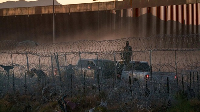 A Texas National Guard soldier holding a pepper ball launcher monitors the concertina wire along the border in El Paso that migrants must cross to surrender to Border Patrol in El Paso, on June 1, 2024. - Texas Tribune / Paul Ratje